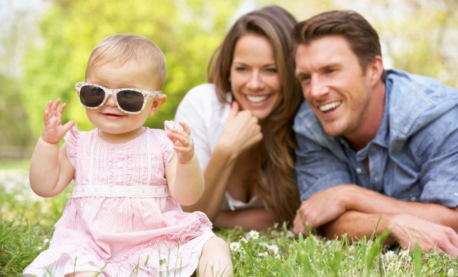 family of three laying on grass